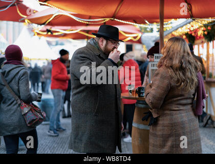 Berlin, Deutschland - Dezember 8, 2017: Die Menschen trinken heißen Glühwein Glühwein am Abend Weihnachtsmarkt auf dem Gendarmenmarkt in Berlin in Deutschland in Europa im Winter. Stockfoto