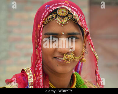 Junge indische Bishnoi Frau trägt ihre kunstvollen Nase und Stirn Schmuck und Lächeln für die Kamera. Stockfoto