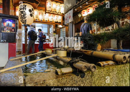 Tradtional shintoistic Wasser Bassin aus Gründen der spirituellen Reinigung in Nishiki Schrein im Herzen von Kyoto erfasst bei Nacht, Japan, November 2018 Stockfoto