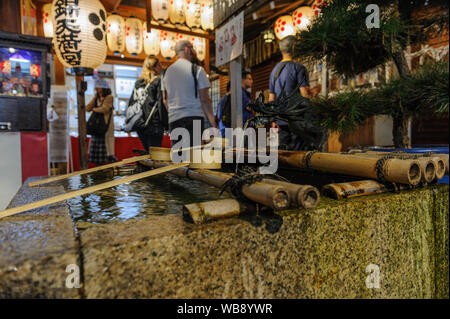 Tradtional shintoistic Wasser Bassin aus Gründen der spirituellen Reinigung in Nishiki Schrein im Herzen von Kyoto erfasst bei Nacht, Japan, November 2018 Stockfoto