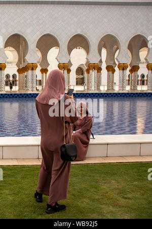 Touristen fotografieren vor dem Haupteingang, Sheikh Zayed Moschee, Abu Dhabi, Vereinigte Arabische Emirate Stockfoto