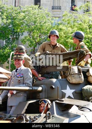 Parade, Avenue du Général Leclerc, mit Menschen in Uniformen und Kostümen, feiern den 75. Jahrestag der Befreiung von Paris im August 25, 1944, Paris, Frankreich. Active Duty general de Räuber der Armee de terre das Tragen der Uniform und tragen weiße Handschuhe, stützte sich auf den Lauf eines 37-mm-Kanone auf einem Amerikanischen geliefert armored Scout Car. Stockfoto