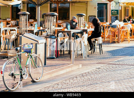 Ljubljana, Slowenien - 14. Januar 2019: Fahrrad- und Touristen essen und trinken in Restaurants, Tischen und Stühlen in Ljubljana Altstadt. Leute, die sich für open air Cafés Stockfoto