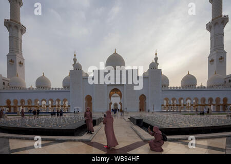 Touristen fotografieren vor dem Haupteingang, Sheikh Zayed Moschee, Abu Dhabi, Vereinigte Arabische Emirate Stockfoto