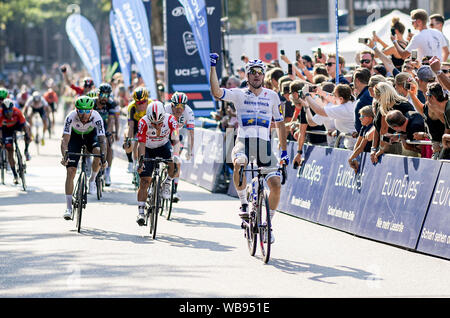 Hamburg, Deutschland. 25 Aug, 2019. Die italienische Elia Viviani (r) vom Team Deceuninck-Quick Schritt überquert die Ziellinie vor dem Peloton der UCI-Welttournee - Cyclassics Rennen. Quelle: Axel Heimken/dpa/Alamy leben Nachrichten Stockfoto