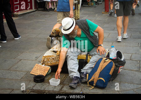 Paris, Frankreich, 7. Juli 2018: Obdachlose und seinem Hund sitzen auf dem Bürgersteig auf die Straßen von Paris zu Füßen der Touristen und Pariser ein Stockfoto