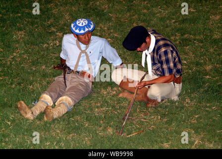 Zwei Gauchos, argentinischen lokalen Cowboys, die auf dem Gras auf der Suche andere, der hängen bleibt, in seinen Händen eine reitpeitsche Stockfoto