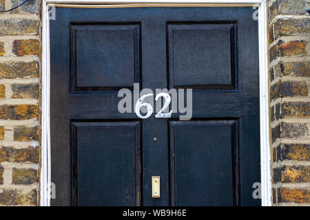 Haus Nummer 62 auf eine schwarze hölzerne Eingangstür mit umliegenden brick Rahmen Stockfoto