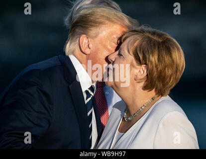 Biarritz, Frankreich. 25. August 2019. Donald Trump, Präsident der USA, küsse die Deutsche Bundeskanzlerin Angela Merkel (CDU) bei einer gemeinsamen Familie Foto auf dem G7-Gipfel zu begrüßen. Die G7-Gipfel findet vom 24. bis 26. August in Biarritz. Foto: Michael Kappeler/dpa Quelle: dpa Picture alliance/Alamy leben Nachrichten Stockfoto