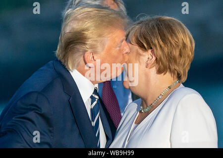 Biarritz, Frankreich. 25. August 2019. Donald Trump, Präsident der USA, küsse die Deutsche Bundeskanzlerin Angela Merkel (CDU) bei einer gemeinsamen Familie Foto auf dem G7-Gipfel zu begrüßen. Die G7-Gipfel findet vom 24. bis 26. August in Biarritz. Foto: Michael Kappeler/dpa Quelle: dpa Picture alliance/Alamy leben Nachrichten Stockfoto