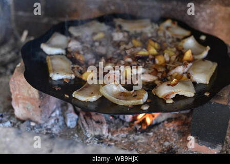 Salo ist in einer Pfanne in einem Ofen auf ein Feuer gebraten. Die Röstung Schmalz im Grill. Barbecue im Sommer im Freien. Schweinefett auf dem Scheiterhaufen. Kochen Street Food. r Stockfoto