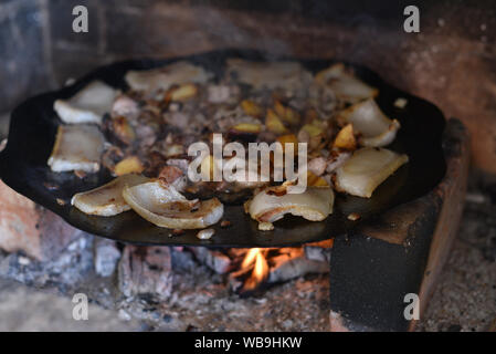 Salo ist in einer Pfanne in einem Ofen auf ein Feuer gebraten. Die Röstung Schmalz im Grill. Barbecue im Sommer im Freien. Schweinefett auf dem Scheiterhaufen. Kochen Street Food. r Stockfoto