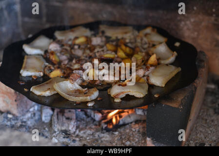 Salo ist in einer Pfanne in einem Ofen auf ein Feuer gebraten. Die Röstung Schmalz im Grill. Barbecue im Sommer im Freien. Schweinefett auf dem Scheiterhaufen. Kochen Street Food. r Stockfoto
