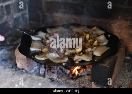 Salo ist in einer Pfanne in einem Ofen auf ein Feuer gebraten. Die Röstung Schmalz im Grill. Barbecue im Sommer im Freien. Schweinefett auf dem Scheiterhaufen. Kochen Street Food. r Stockfoto