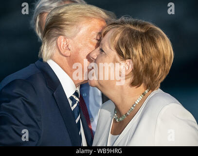 Biarritz, Frankreich. 25. Aug 2019. Donald Trump, Präsident der USA, küsse die Deutsche Bundeskanzlerin Angela Merkel (CDU) bei einer gemeinsamen Familie Foto auf dem G7-Gipfel zu begrüßen. Die G7-Gipfel findet vom 24. bis 26. August in Biarritz. Quelle: dpa Picture alliance/Alamy leben Nachrichten Stockfoto