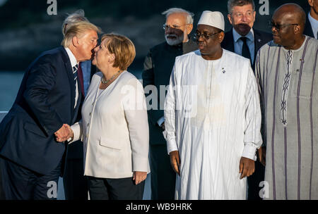 Biarritz, Frankreich. 25. Aug 2019. Donald Trump, Präsident der USA, küsse die Deutsche Bundeskanzlerin Angela Merkel (CDU), wie Sie die G7-Familie Fotographie begrüßt, während (L-R), Narendra Modi, Premierminister Macky Sall, der Präsident von Senegal, und Roch Marc Christian Kabore, Präsident von Burkina Faso, Watch (L-R). Die G7-Gipfel findet vom 24. bis 26. August in Biarritz. Quelle: dpa Picture alliance/Alamy leben Nachrichten Stockfoto