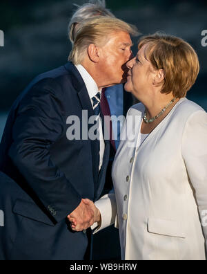 Biarritz, Frankreich. 25. Aug 2019. Donald Trump, Präsident der USA, küsse die Deutsche Bundeskanzlerin Angela Merkel (CDU) bei einer gemeinsamen Familie Foto auf dem G7-Gipfel zu begrüßen. Die G7-Gipfel findet vom 24. bis 26. August in Biarritz. Quelle: dpa Picture alliance/Alamy leben Nachrichten Stockfoto