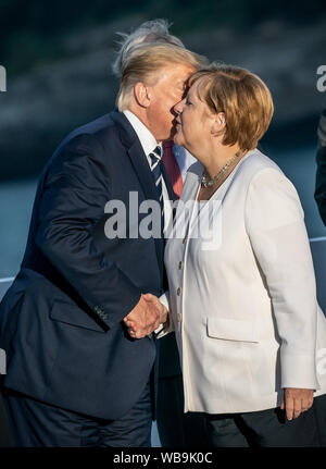 Biarritz, Frankreich. 25. Aug 2019. Donald Trump, Präsident der USA, küsse die Deutsche Bundeskanzlerin Angela Merkel (CDU) bei einer gemeinsamen Familie Foto auf dem G7-Gipfel zu begrüßen. Die G7-Gipfel findet vom 24. bis 26. August in Biarritz. Quelle: dpa Picture alliance/Alamy leben Nachrichten Stockfoto