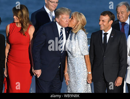 Der französische Präsident Emmanuel Längestrich beobachtet, wie seine Frau Brigitte Längestrich küsse Präsident Donald Trump, wie er mit der ersten Dame Melania Trump steht, wie Sie andere Führer der Welt für die Familie Foto auf dem G7-Gipfel in Biarritz, Frankreich. Stockfoto