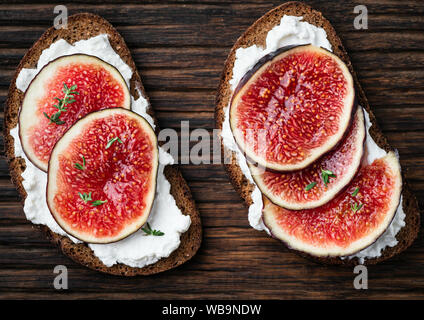 Roggen healhy Vorspeise Bruschetta mit Feigen, ricotta Käse und Thymian auf einem hölzernen Hintergrund, Ansicht von oben Stockfoto