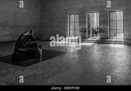 Skulptur "Mutter mit ihrem toten Sohn" von Käthe Kollwitz in der Neuen Wache, Berlin, mit 3 Besucher in Tür Stockfoto