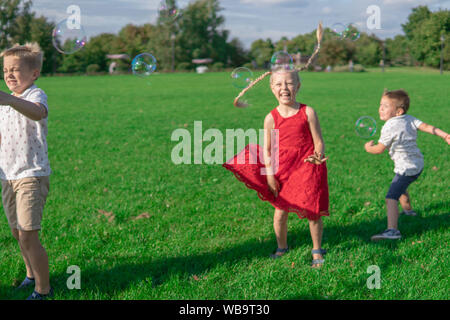 Russland, Moskau - August 24, 2019. Kinder start Seifenblasen, laufen rund um den grünen Bereich, glücklich liebend Stockfoto