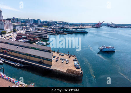 Blick auf die Innenstadt von Seattle, WA, aus dem großen Rad, eine Gondelfahrt am Ende der Pier 57 im Elliot Bay. Mit einer Gesamthöhe von 175 Metern, war es das höchste Riesenrad an der Westküste der Vereinigten Staaten, wenn es am 29. Juni 2012 geöffnet. Einer der Seattle touristischen Boote kommt im Dock und ein Seattle ferry kann im Hintergrund gesehen werden. Stockfoto