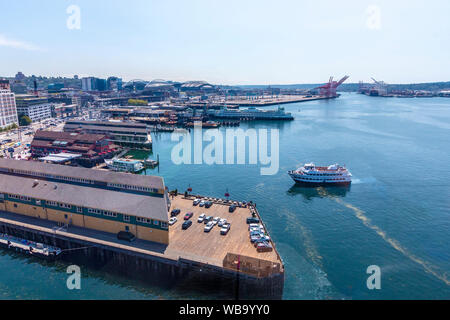 Blick auf die Innenstadt von Seattle, WA, aus dem großen Rad, eine Gondelfahrt am Ende der Pier 57 im Elliot Bay. Mit einer Gesamthöhe von 175 Metern, war es das höchste Riesenrad an der Westküste der Vereinigten Staaten, wenn es am 29. Juni 2012 geöffnet. Einer der Seattle touristischen Boote kommt im Dock und ein Seattle ferry kann im Hintergrund gesehen werden. Stockfoto