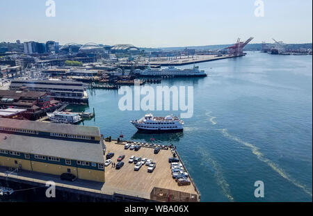 Blick auf die Innenstadt von Seattle, WA, aus dem großen Rad, eine Gondelfahrt am Ende der Pier 57 im Elliot Bay. Mit einer Gesamthöhe von 175 Metern, war es das höchste Riesenrad an der Westküste der Vereinigten Staaten, wenn es am 29. Juni 2012 geöffnet. Einer der Seattle touristischen Boote kommt im Dock und ein Seattle ferry kann im Hintergrund gesehen werden. Stockfoto