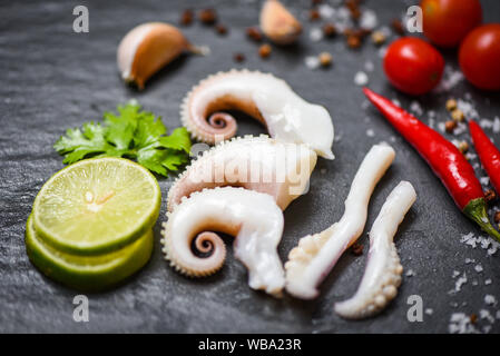 Tintenfisch Salat mit Zitrone Kräuter und Gewürze auf dunklem Hintergrund Top View/Tentakeln Krake warme Vorspeise essen heiß und würzig Chili Sauce seafood Cooke Stockfoto