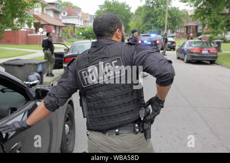 Detroit Police Department Special Operations Officer Schubladen sein Gewehr, wie er sich vorbereitet, um ein Haus zu nähern, wie sie für einen Verdächtigen, Detroit, Michigan, USA Stockfoto