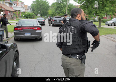 Detroit Police Department Special Operations Officer Schubladen sein Gewehr, wie er sich vorbereitet, um ein Haus zu nähern, wie sie für einen Verdächtigen, Detroit, Michigan, USA Stockfoto