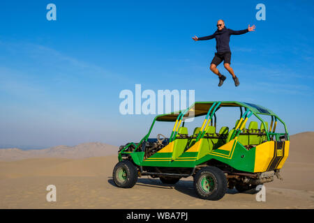 Männliche Touristen springen auf einem Dune Buggy, Huacachina Oase in der Wüste, Ica, Peru Stockfoto