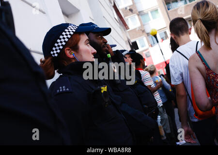 London, Großbritannien. 25 Aug, 2019. Polizisten Wachen in Chepstow Road während der Eröffnung Tag der 2019 Notting Hill Carnival. Bis zu eine Million Menschen werden erwartet, durch die Straßen von Notting Hill zu packen und den umliegenden Gebieten im Laufe der zweitägigen Veranstaltung. Die jährliche Feier des afro-karibischen Kultur nimmt jeder Platz August Bank Holiday Wochenende. Credit: SOPA Images Limited/Alamy leben Nachrichten Stockfoto