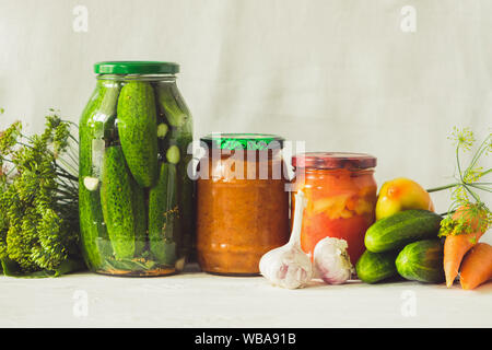 Fermentierte oder canning verschiedene Gemüse zucchini Karotten Gurken in Gläsern auf einem Tisch, einem hellen Hintergrund. Verarbeitung der Herbst Ernte. Natürliche Tropfen Stockfoto