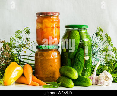 Fermentierte oder canning verschiedene Gemüse zucchini Karotten Gurken in Gläsern auf einem Tisch, einem hellen Hintergrund. Verarbeitung der Herbst Ernte. Natürliche Tropfen Stockfoto