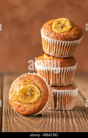 Hausgemachte Banana Muffins in einem Stapel auf braunem Grund. Gesunde vegane Nachspeise. Close-up selektiven Fokus. Kopieren Sie Platz. Vertikale Rahmen. Stockfoto