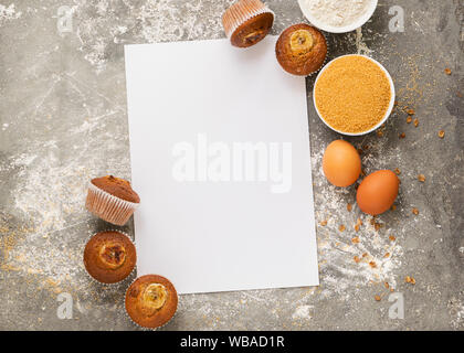 Hausgemachte Banana Muffins und Zutaten für das Kochen auf ein weißes leeres Blatt gelegt. Gesunde vegane Nachspeise. Gesunde Ernährung Konzept. Kopieren Sie Platz. Fl Stockfoto