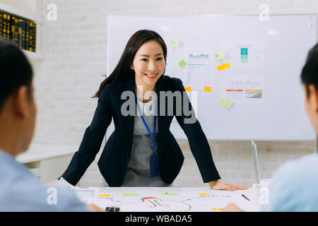 Asiatische ausgereifte Frau lächelnd und diskutieren mit anderen Männern. Gruppe von Geschäftsleuten in der Konferenz. Stockfoto