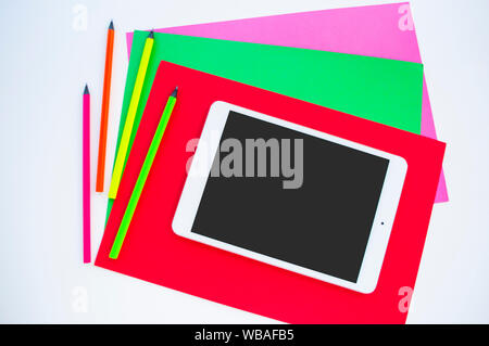 Bunte Papier, neon Bleistifte und Tablet auf weißem Hintergrund mit Copyspace. Flach Stil. Zurück zum Konzept der Schule. Stockfoto