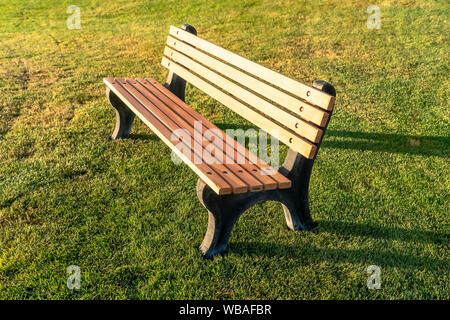 Nahaufnahme eines leeren outdoor Bank gegen pulsierende grüne Gräser an einem sonnigen Tag Stockfoto