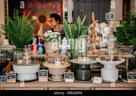 Februar 11, 2014 in Chiang Mai, Thailand - Cafe Inneneinrichtung altes Holz Zähler mit tropischen Pflanzen Töpfe und Schalen aus Keramik mit sortierten Bäckerei Gebäck Stockfoto