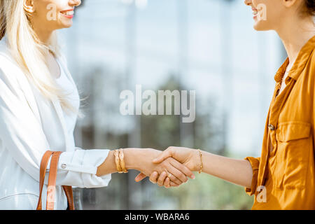 Zwei Geschäftsfrauen in einen Deal schütteln handsoutdoors, Nahaufnahme Stockfoto