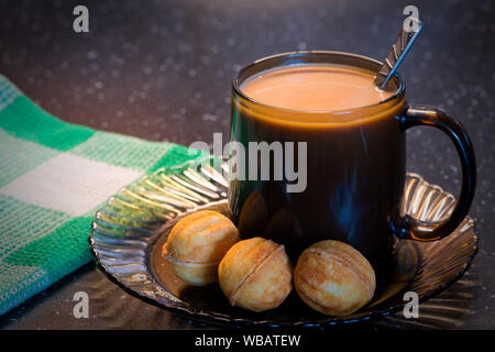 Heißer Frühstückskaffee mit drei süßen Nüssen auf Glasplatte. Stillleben Fotografie von leckeren Frühstück. Stockfoto