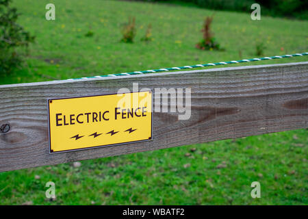 Elektrozaun Warnschild auf hölzernen Pfosten. Stockfoto