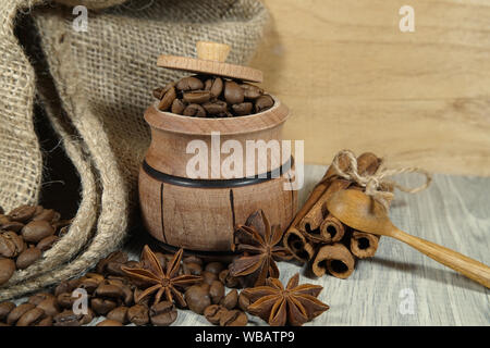 Kaffeebohnen überlaufen von einem kleinen Topf, würzige, Sternanis und Zimtstangen in einem rustikalen noch Leben auf einem Holztisch mit Platz kopieren Stockfoto