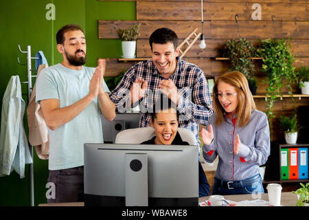 Business Partner in Start-up-Büro feiert ein großer Verkauf. Sie alle sind glücklich und klatschen Stockfoto