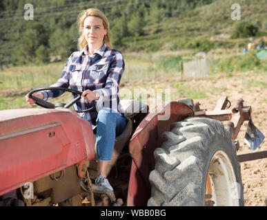 Lächelnd weibliche Bauer auf der Farm Traktor in ihrer Arbeit kleinfarm Stockfoto