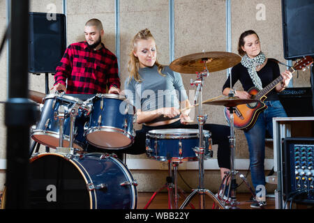 Emotionale happy positive weibliche Drummer mit ihren Bandkollegen üben im Proberaum leidenschaftlich Stockfoto