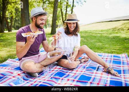 Junges Paar auf Picknick im Park zusammen essen und gießt Wasser in Glas Stockfoto